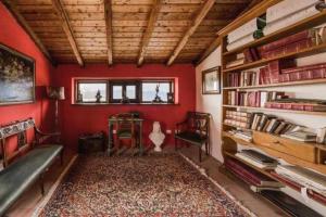 uma sala de estar com paredes vermelhas e uma estante de livros em Torre del 1300 Un atto damore em Castiglione