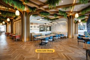 um restaurante com mesas, cadeiras e plantas em The First Collection Waterfront em Dubai