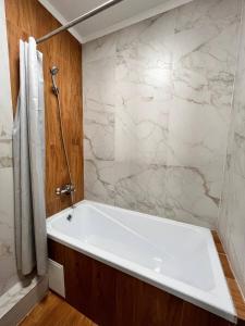 ЖК Коркем 4 في أستانا: حوض استحمام أبيض في حمام مع دش