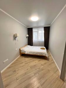 een slaapkamer met een bed en een houten vloer bij ЖК Коркем 4 in Astana