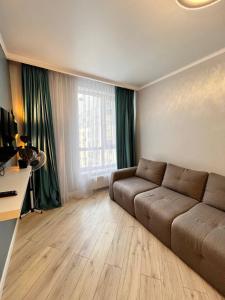ЖК Коркем 4 في أستانا: غرفة معيشة مع أريكة ونافذة كبيرة