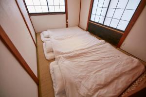 two beds in a small room with two windows at Hakone Yumoto Base in Hakone +22 photos