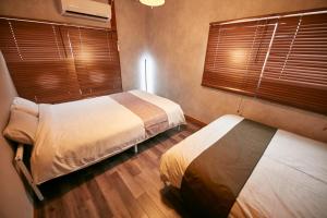 two beds in a room with two windows at Hakone Yumoto Base in Hakone