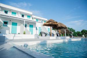 a swimming pool next to a building with a thatch umbrella at Woywoy Paradise in Bira