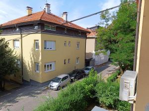 ein gelbes Haus mit zwei Autos davor geparkt in der Unterkunft LuxApart Dzidzikovac City Centar free parking in Sarajevo
