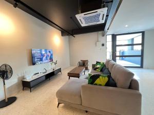 uma sala de estar com um sofá e uma televisão em Galaria 4BR 17Pax NearTC, DinosaurLand, PS4, Netflix em Kuantan