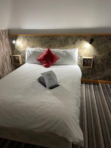 a large white bed with a book on it at The Six Bells Hotel in Enfield