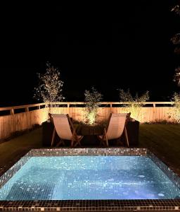 a swimming pool at night with two chairs and a table at The Durham Ox in Crayke