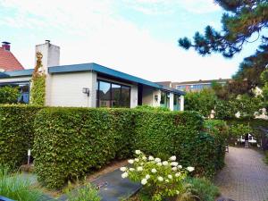 a house behind a hedge with flowers in front of it at Villa Park in Bennebroek +11 photos
