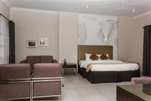 pokój hotelowy z łóżkiem i 2 krzesłami w obiekcie Cedar Place w mieście Blantyre