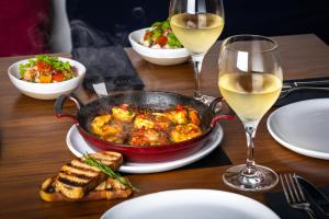 a table with a pot of food and glasses of wine at JA The Resort - JA Palm Tree Court in Dubai