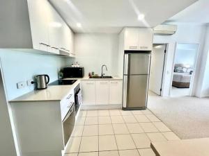 een keuken met witte kasten en een roestvrijstalen koelkast bij Apartment on Palmer in Townsville