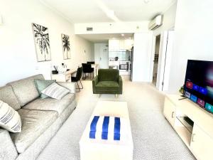ein Wohnzimmer mit einem Sofa und einem TV in der Unterkunft Apartment on Palmer in Townsville