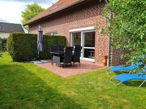 a patio with a table and chairs and an umbrella at Ferienhaus Kleine Möwe in Altfunnixsiel