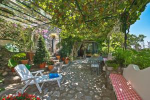 einen Garten mit einer Pergola, Stühlen und Pflanzen in der Unterkunft YourHome - Maison Iolanda Positano in Positano