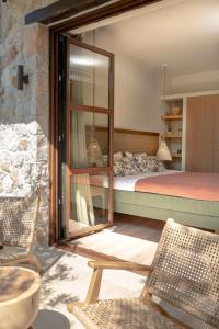 a bedroom with a bed and a mirror and chairs at MAISON - ELEA in Ierissos