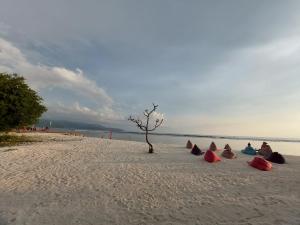 a group of people sitting in the sand on a beach at Sahara Sands Guest House - Gili Trawangan in Gili Trawangan
