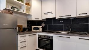 cocina con armarios blancos y nevera de acero inoxidable en Della Grazia 1-2 A en Bolonia