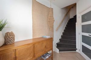 a hallway with a staircase with a wooden dresser and a stair case at Bamboa Beachhouse in Zandvoort