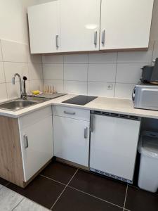 uma cozinha com armários brancos e um lavatório em Studioapartment/Messewohnung em Colônia