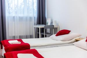 two beds with red pillows in a room with a window at Pokoje gościnne OSiR in Zamość
