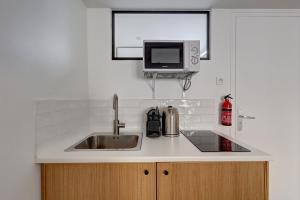 eine Küche mit einer Spüle und einer Mikrowelle in der Unterkunft 135 Suite Franck - Charmant Studio à Paris in Paris