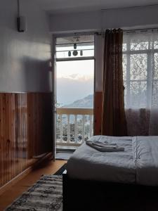 a bedroom with a bed and a large window at Yalung Homestay in Darjeeling