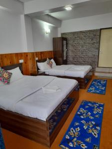 2 camas en una habitación con 2 alfombras en Yalung Homestay, en Darjeeling