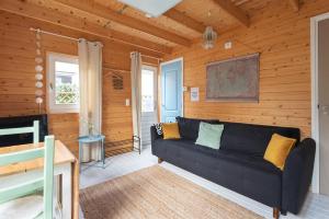 sala de estar con sofá negro y paredes de madera en Moyo Kijani, en Zandvoort