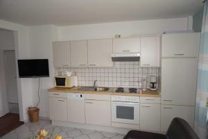 a kitchen with white cabinets and a sink at Ferienhaus Ortgies in Carolinensiel