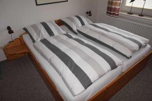 a bed with black and white striped pillows on it at Ferienhaus Ortgies in Carolinensiel