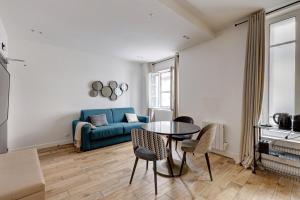 een woonkamer met een blauwe bank en een tafel bij 152 Suite Sylvie - Superb apartment in Paris in Parijs