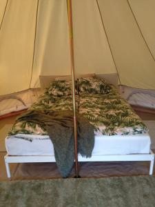 a bed in a tent with a blanket on it at Ruustinnan telttamajoitukset in Saarijärvi