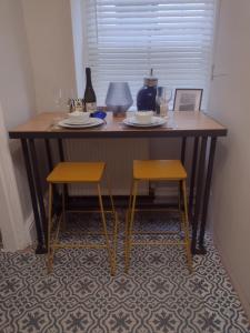 a table with two chairs and a table with plates and glasses at The Mews Cottage in Penzance