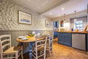 une cuisine avec des placards bleus et une table et des chaises en bois dans l'établissement Yew Tree Cottage, à Blakeney