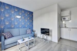 uma sala de estar com um sofá azul e uma cozinha em 807 Suite Cosy - Superb Apartment em Bagnolet