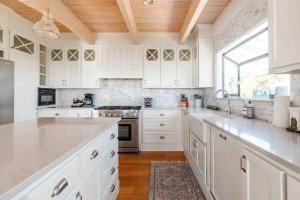 サマーランドにあるSummer Beach Houseの白いキャビネットと木製の天井が備わるキッチン
