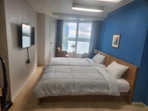 a bedroom with a large bed with a blue wall at Haeundae Bada Residence in Busan