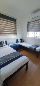 Cette chambre comprend 3 lits et une fenêtre avec des stores. dans l'établissement Casa de M&I, à General Santos
