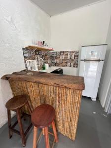 a kitchen with a counter with two stools and a refrigerator at Casa Recanto - Villa Uryah in Caraíva