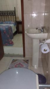 a bathroom with a toilet and a sink and a bed at Hospedaria Meu Lar in Rio das Ostras