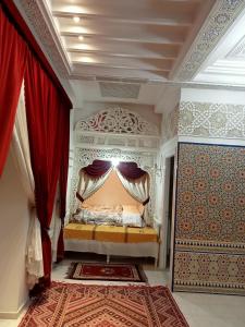 a bedroom with a bed with red curtains and a rug at Chez Mme Jaouida in El Mourstane