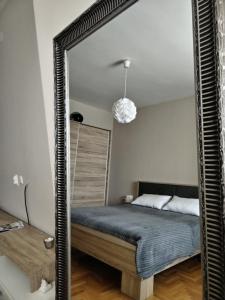 a mirror in front of a bed in a bedroom at TEA APARTMAN in Niš