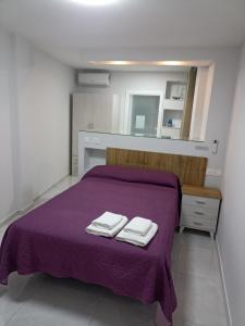 una camera da letto con un letto viola e due asciugamani di oasis en Tenerife 3 a El Escobonal
