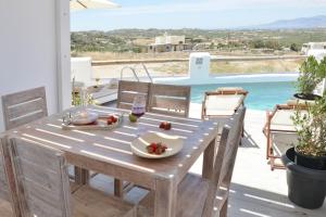 a wooden table with food and a glass of wine at Villa Areti Naxos in Glinado Naxos