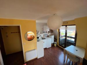 uma cozinha com paredes amarelas, uma mesa e um candeeiro em L'Horizon em Villers-sur-Mer