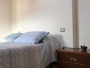 a bed with a pillow and a wooden nightstand at Mansarda Raffaello in Seregno
