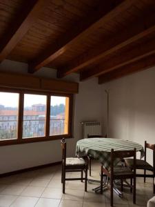 comedor con mesa, sillas y ventanas en Mansarda Raffaello, en Seregno