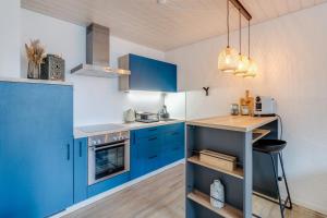 een kleine keuken met blauwe kasten en een aanrecht bij Bijou Sternen - Bergluft und Seeträume in Faulensee