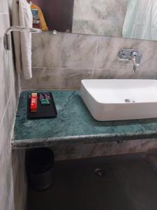 La salle de bains est pourvue d'un lavabo et d'un livre sur un comptoir. dans l'établissement Jim Corbett Tiger Resort, à Belparāo